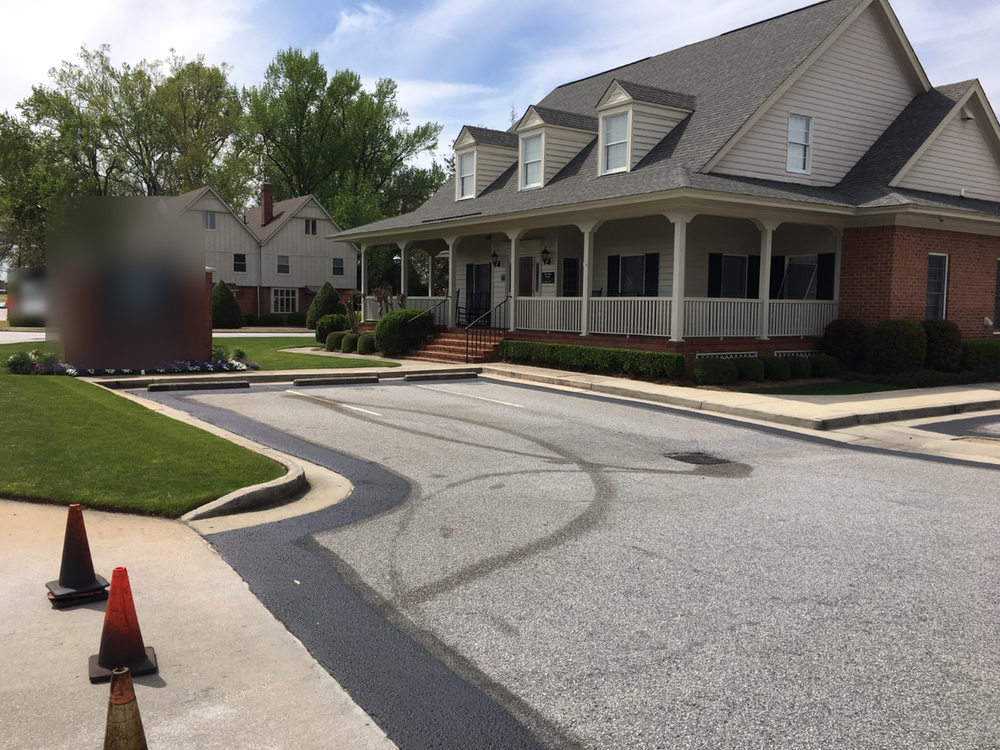 Before: gray entrance drive with tire marks curving past a brick monument sign toward a two-story building